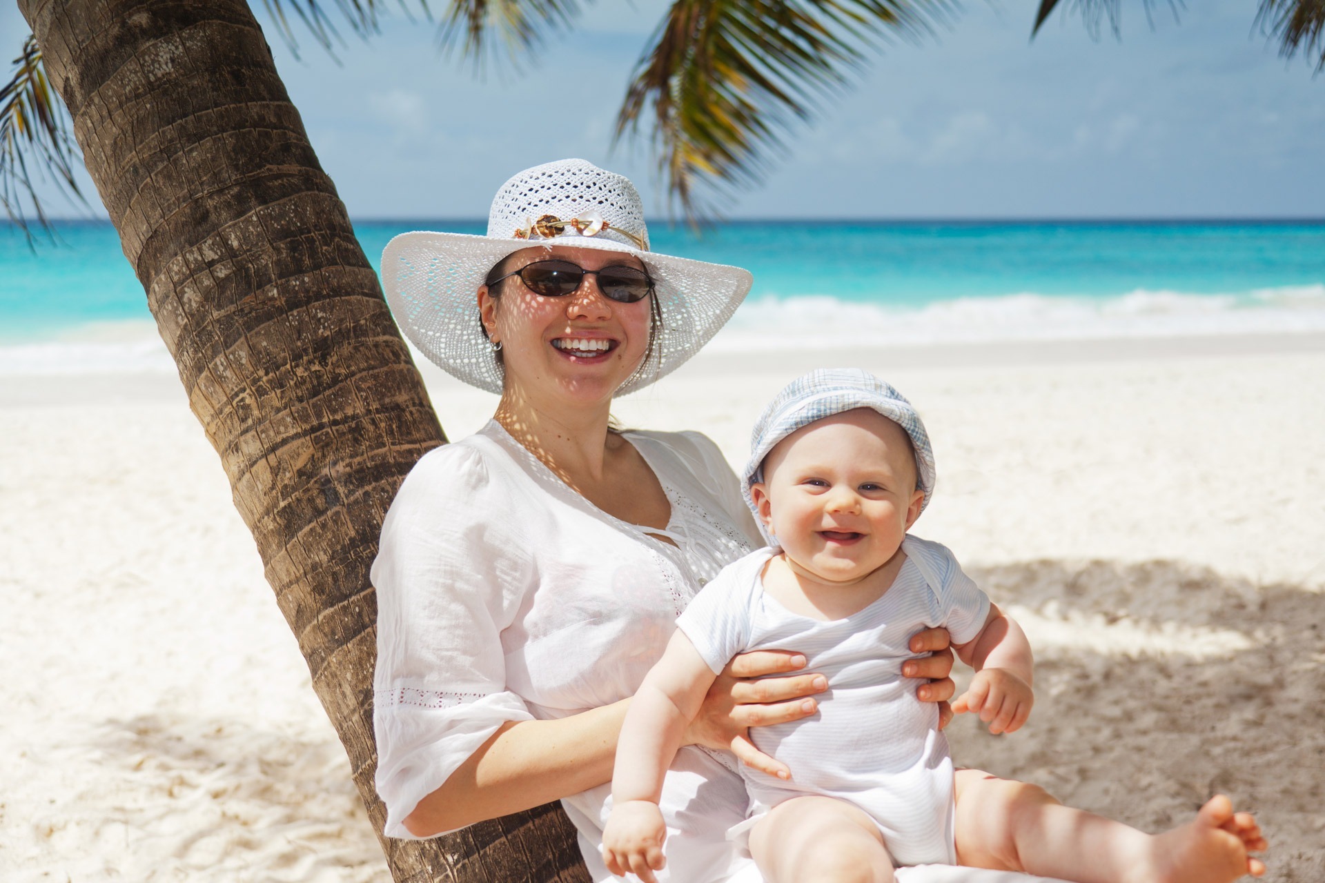 Mum with child on lap sitting on a tree at the beach